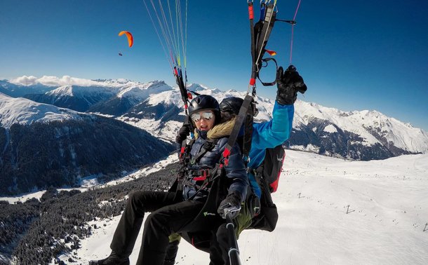 Tandem paragliding flight in the middle of the snowy mountains of Davos Klosters.
