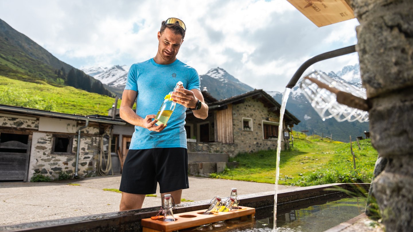 Dario Cologna macht eine Pause auf seinem «Bike & Hike»-Abenteuer an der Sirup-Bar auf Alp Sardasca in Klosters.